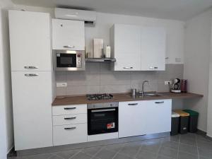 a kitchen with white cabinets and a microwave at Villa del Limone in Sellia Marina +15 photos