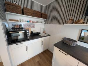 a kitchen with white cabinets and a microwave at ParkNest - Apartment am Kurpark in Bad Klosterlausnitz