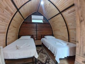 two beds in a room with wooden walls at Kalinka pansiyon in Cıralı