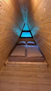 a small bed in a wooden room with a window at Cabana La Poiata in Valea Chioarului