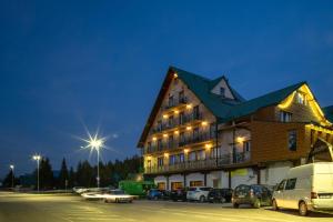ein großes Gebäude mit auf einem Parkplatz abgestellten Autos in der Unterkunft Hotel Enigma in Žabljak