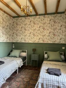 two beds in a room with floral wallpaper at Maison sur Coline in Lectoure +22 photos