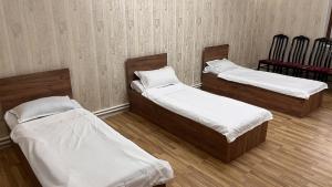 three beds in a room with two red chairs at DARAI guest house Hostel Turkistan in Türkistan