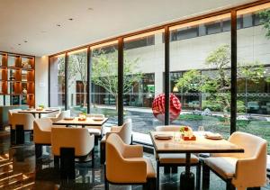 a restaurant with tables and chairs and large windows at Bristoria Hotel Yangzhou in Yangzhou