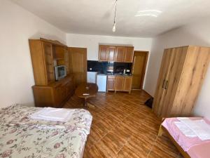 a room with a kitchen with a bed and wooden cabinets at Apartmani Adelisa in Šušanj