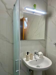 a white bathroom with a sink and a mirror at Armonia Apartments in Archangelos +22 photos