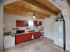 a kitchen with red cabinets and a white refrigerator at Erdőszéli vendégház in Ghiduţ