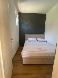 a small bedroom with a bed with a blackboard on the wall at Apartmani Adelisa in Šušanj +6 photos