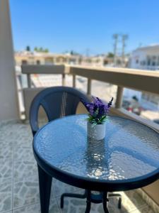 a blue table with a vase with purple flowers on it at Armonia Apartments in Archangelos