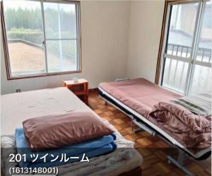 two beds in a room with a window at 海っぺり宮崎 in Miyazaki