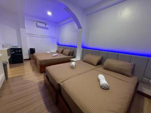 a room with two beds in a room with purple lights at Villa Virtud Beach Resort in Alegria