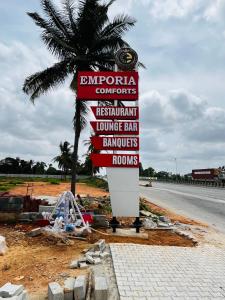 a sign on the side of a road with a palm tree at Emporia comforts in Devanhalli