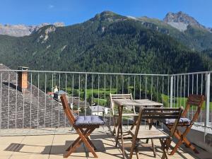 two chairs and a table on a balcony with mountains at Chasa Bellavista in Ardez