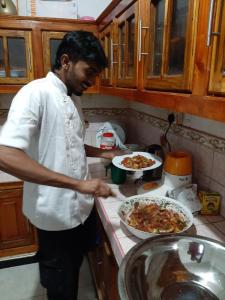 a man standing in a kitchen preparing a pizza at The Green Heritance in Habarana