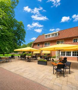 a patio with tables and chairs and yellow umbrellas at Hotel de Landmarke Ootmarsum in Groot-Agelo