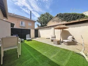 a backyard with a lawn with chairs and an umbrella at Le Cocon Tropical - Cosy, Clim, Centre-ville, Jardinet, 2 personnes in Miramas