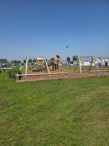 a park with a playground with two swings at Lownie lodge in Leysdown-on-Sea