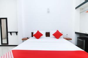 a bedroom with a white bed with red pillows at Lodge 52 Negombo in Negombo