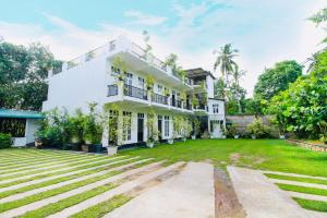 an exterior view of a white house with a yard at Lodge 52 Negombo in Negombo
