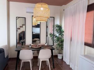 a dining room with a black table and white chairs at La Escapada in El Ronquillo