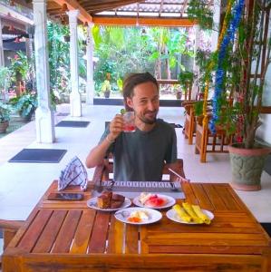 a man sitting at a table with a glass of juice at The Green Heritance in Habarana