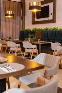 a restaurant with tables and chairs and a tv at Pollock Hotel, Ribarska Banja in Ribarska Banja