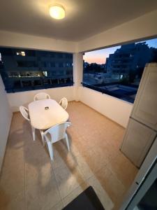 a white dining room with a table and two windows at Lux Family Suite & Pool in Larnaca