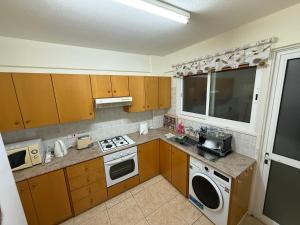 a kitchen with wooden cabinets and a washer and dryer at Lux Family Suite & Pool in Larnaca +2 photos