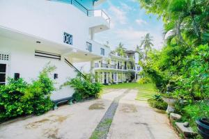 an exterior view of a white building with trees at Lodge 52 Negombo in Negombo