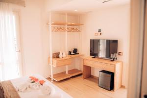 a white room with a television and a desk with a bed at Lentischi Hotel - Adults Only in Villasimius
