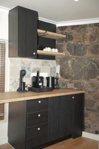 a kitchen with black cabinets and a stone wall at Aprosmeno House 5 in Agros