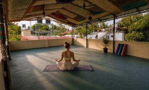 a woman sitting in a yoga position on the floor at Gypsy Walker in Varkala