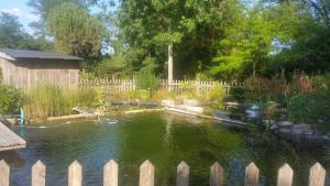 a pond in a garden with a wooden fence at séjourner en yourte in Gans