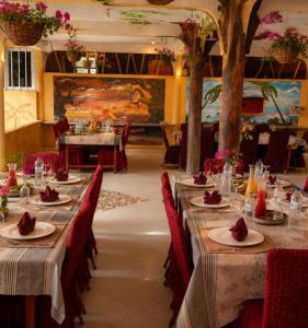 a dining room with long tables and red chairs at Ecogîte Dégg-Jàmm in Mbour