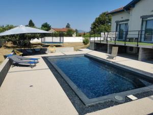 a swimming pool with an umbrella next to a house at La Cigaline in Anneyron