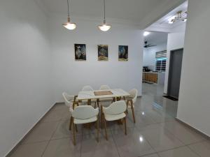 a dining room with a table and white chairs at D'Biru Homestay Segamat in Segamat