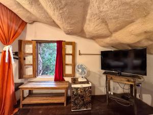 a living room with a flat screen tv and a window at Pousada Flor de Açucena in Igatu