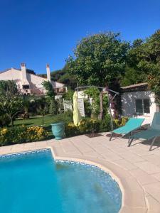 a swimming pool next to a patio with a blue chair at Le Jardin d Eden in Sainte-Maxime