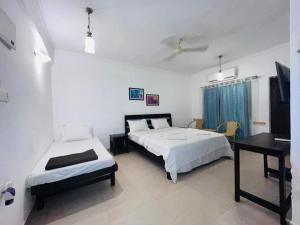 a bedroom with two beds and a desk in it at Baga Central Studio Apartment in Baga