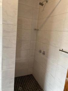 a shower with a white tiled shower stall at Florence contractors accomodation in Standerton