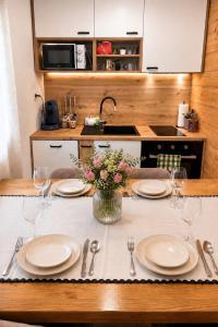 a table with plates and glasses and a vase of flowers at Apartman Andrej in Kolarec +3 photos