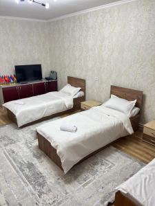 a bedroom with two beds and a television in it at DARAI guest house Hostel Turkistan in Türkistan