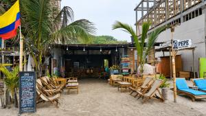 an outdoor patio with chairs and tables and palm trees at Hostal Nomadax Tayrona in El Zaino