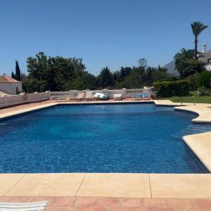 a large swimming pool with blue water at Room in Estepona +25 photos