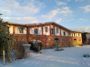 a large brick building with snow on the ground at Ferien am Schloss - Wohnung 2 "die Maus", Ferienwohnung am Badesee in Behren-Lübchin