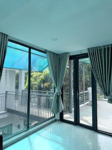 a room with large windows and a view of a balcony at Mango Villa Long Hải Beach in Long Hai