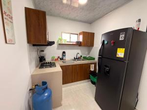 a kitchen with a black refrigerator and a sink at El Gran Jeronimo Hostal Rincon del Mar in Rincón