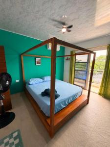 a bedroom with a canopy bed with a green wall at El Gran Jeronimo Hostal Rincon del Mar in Rincón