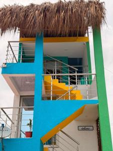 a building with a thatched roof with yellow and blue stairs at El Gran Jeronimo Hostal Rincon del Mar in Rincón