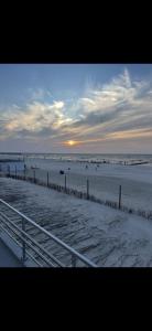 a beach at sunset with people in the water at Przytulna Kawalerka Łeba in Łeba